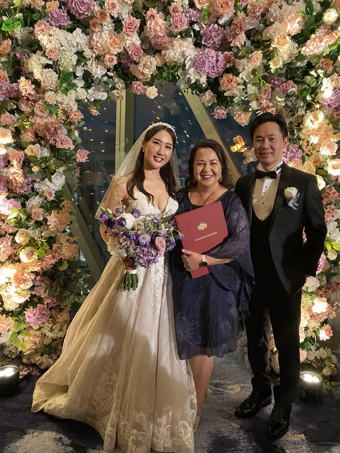 Josephine with a couple under a full floral arch